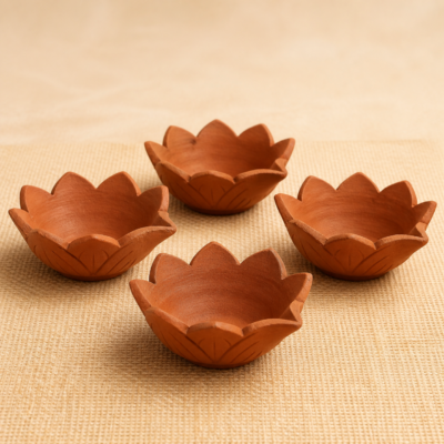 Set of four handcrafted terracotta lotus diyas on a natural jute surface