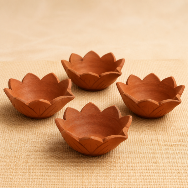 Set of four handcrafted terracotta lotus diyas on a natural jute surface