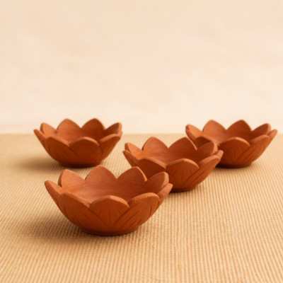 Side profile of four handcrafted terracotta lotus diyas showing their carved exterior